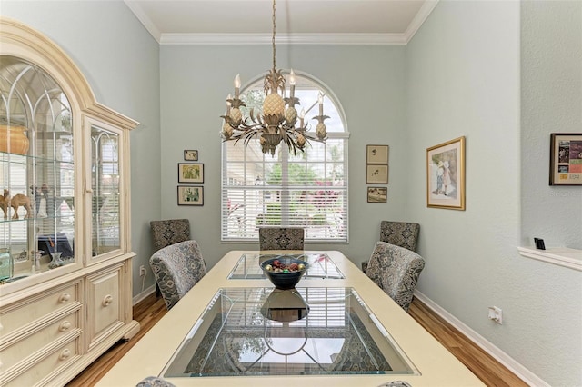 dining space with light hardwood / wood-style floors, an inviting chandelier, and crown molding