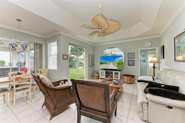 tiled living room featuring ceiling fan, a tray ceiling, and crown molding