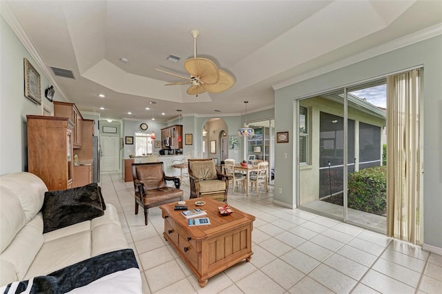 living room featuring light tile patterned floors, ceiling fan, a tray ceiling, and crown molding