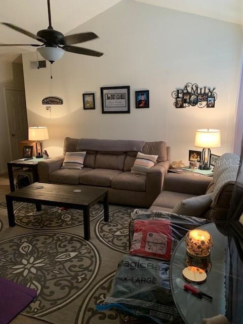 living room with ceiling fan and vaulted ceiling