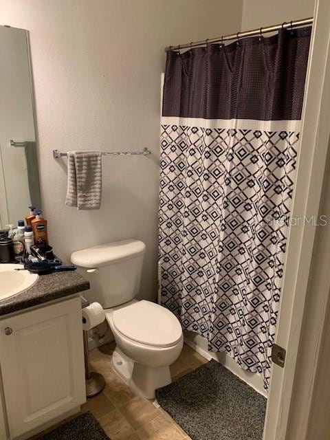 bathroom featuring toilet, a shower with shower curtain, and vanity