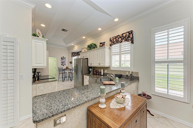 kitchen featuring stainless steel appliances, white cabinetry, kitchen peninsula, and light stone countertops