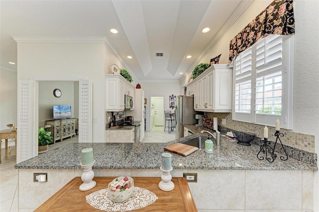 kitchen with sink, stainless steel appliances, white cabinetry, and light stone counters