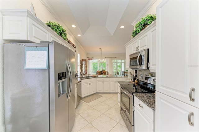 kitchen with white cabinets, appliances with stainless steel finishes, ornamental molding, and a tray ceiling