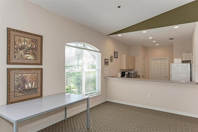 kitchen featuring white fridge, plenty of natural light, lofted ceiling, and carpet flooring