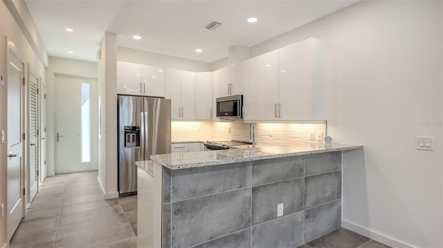 kitchen featuring stainless steel appliances, white cabinetry, a peninsula, and light stone counters