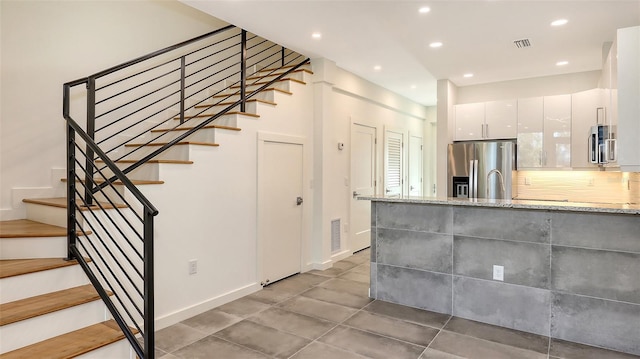 kitchen with modern cabinets, appliances with stainless steel finishes, light stone counters, white cabinetry, and recessed lighting