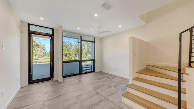 empty room featuring visible vents, baseboards, stairs, floor to ceiling windows, and recessed lighting