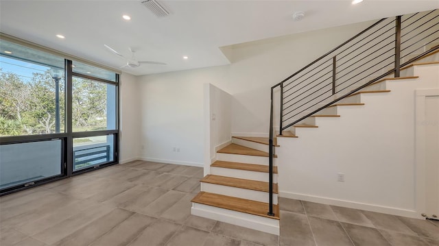 stairway featuring ceiling fan, recessed lighting, visible vents, baseboards, and expansive windows