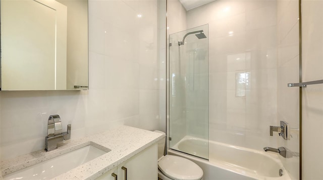 bathroom featuring tasteful backsplash, toilet, shower / tub combination, vanity, and tile walls