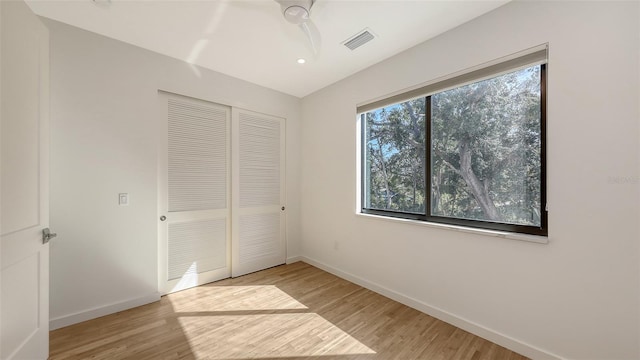 unfurnished bedroom featuring light wood-style flooring, a ceiling fan, visible vents, baseboards, and a closet