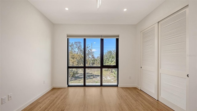 unfurnished bedroom featuring recessed lighting, a closet, baseboards, and light wood finished floors