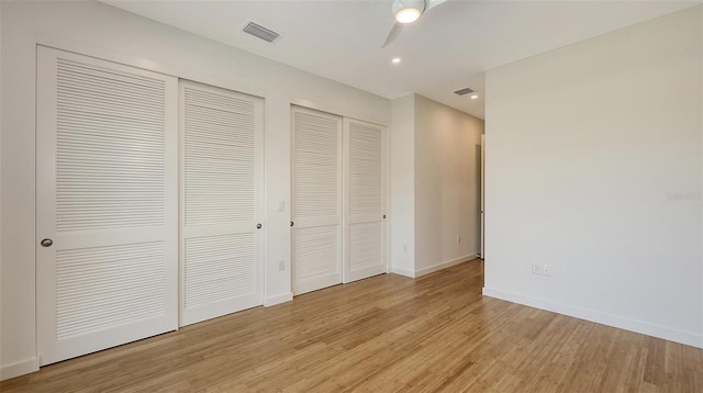 unfurnished bedroom featuring light wood-style flooring, recessed lighting, visible vents, baseboards, and multiple closets