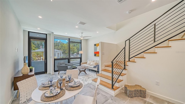 dining area featuring ceiling fan and a wall of windows