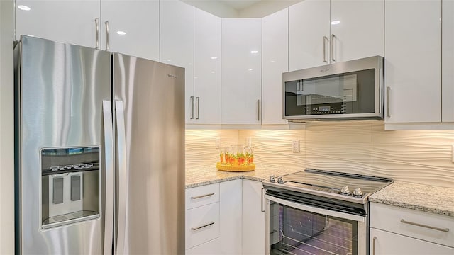 kitchen with appliances with stainless steel finishes, decorative backsplash, white cabinetry, and light stone counters