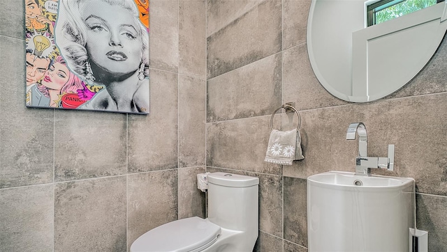 bathroom featuring toilet and tile walls