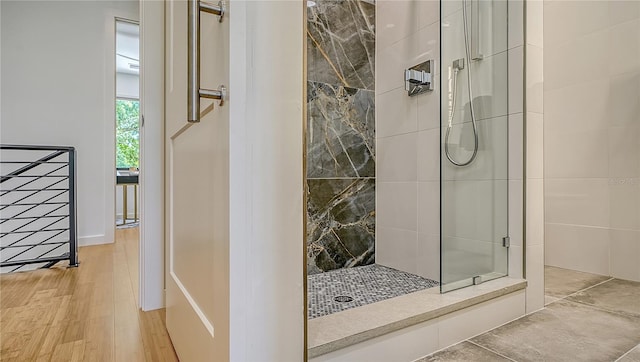 bathroom with hardwood / wood-style flooring and tiled shower