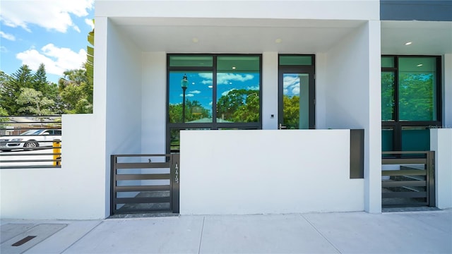 view of exterior entry with stucco siding and fence