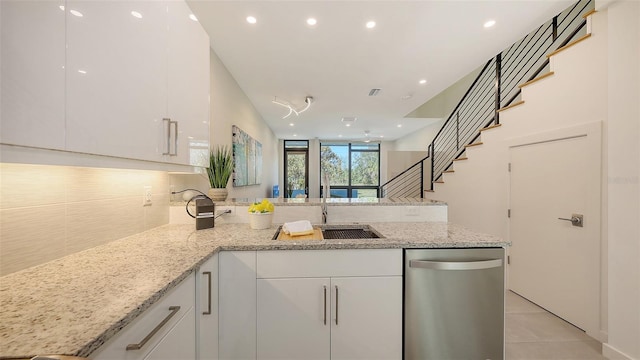 kitchen featuring backsplash, white cabinetry, a peninsula, light tile patterned floors, and light stone countertops