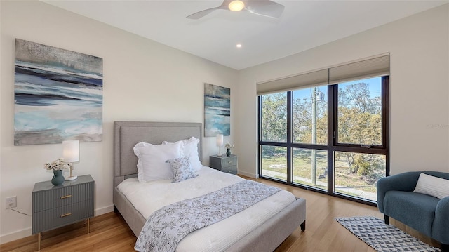 bedroom featuring ceiling fan, baseboards, multiple windows, and wood finished floors