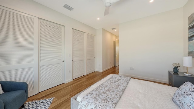 bedroom featuring visible vents, two closets, wood finished floors, recessed lighting, and baseboards