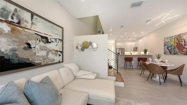 living area featuring light tile patterned floors, visible vents, recessed lighting, and stairs