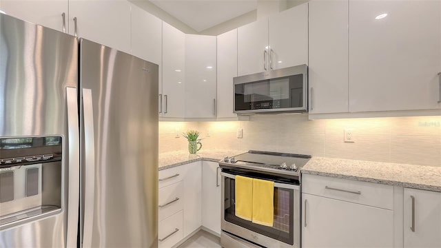 kitchen featuring stainless steel appliances, light stone countertops, tasteful backsplash, and white cabinetry