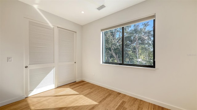 unfurnished bedroom featuring a closet, visible vents, baseboards, and wood finished floors