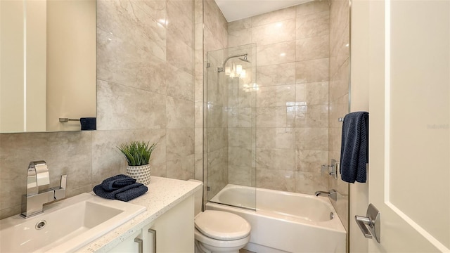 full bath featuring toilet, backsplash, tile walls, washtub / shower combination, and vanity