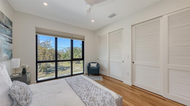 bedroom featuring visible vents, light wood finished floors, baseboards, recessed lighting, and two closets