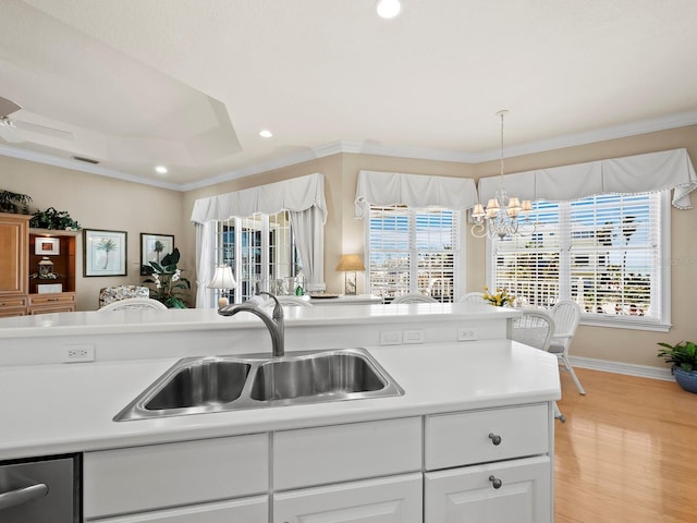 kitchen with sink, a notable chandelier, ornamental molding, light hardwood / wood-style floors, and white cabinets