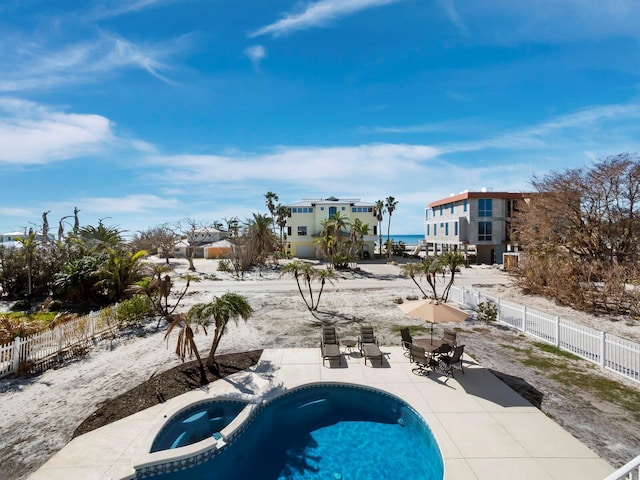 view of pool featuring an in ground hot tub, a water view, and a patio area