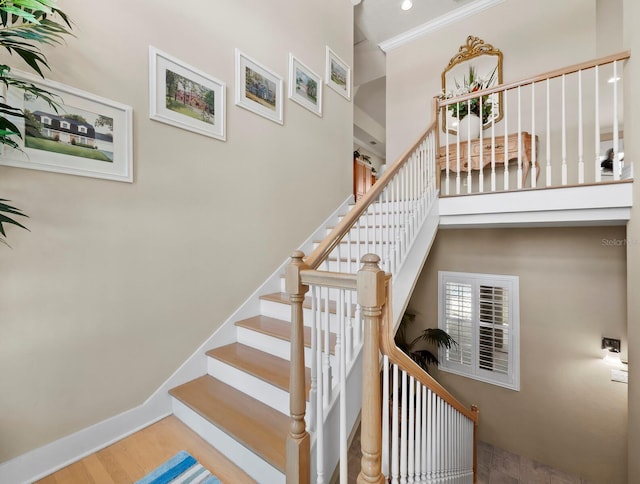 staircase featuring hardwood / wood-style flooring, crown molding, and a towering ceiling