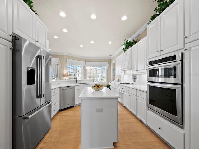 kitchen featuring white cabinetry, light hardwood / wood-style flooring, ornamental molding, a kitchen island, and stainless steel appliances