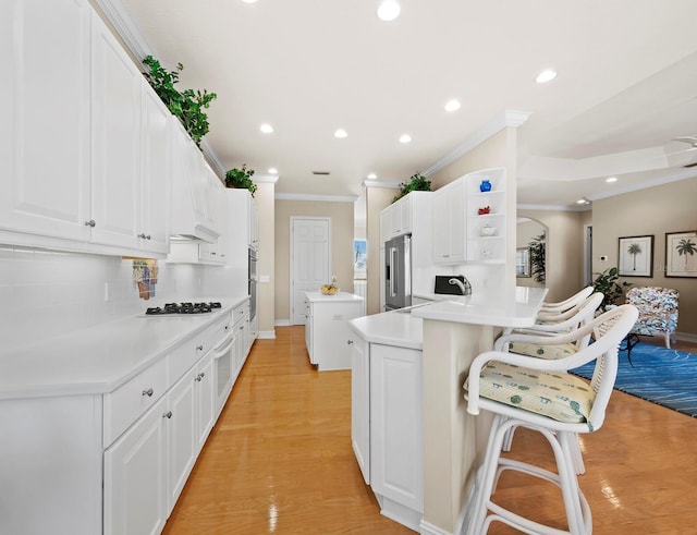 kitchen with backsplash, white cabinets, a kitchen bar, high end refrigerator, and kitchen peninsula