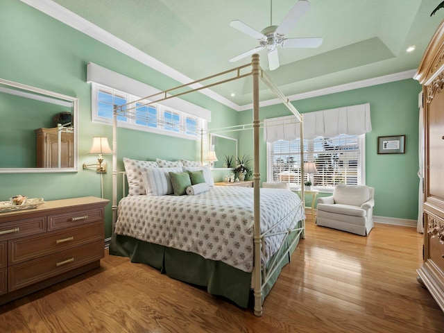 bedroom featuring ceiling fan, ornamental molding, a raised ceiling, and light hardwood / wood-style flooring