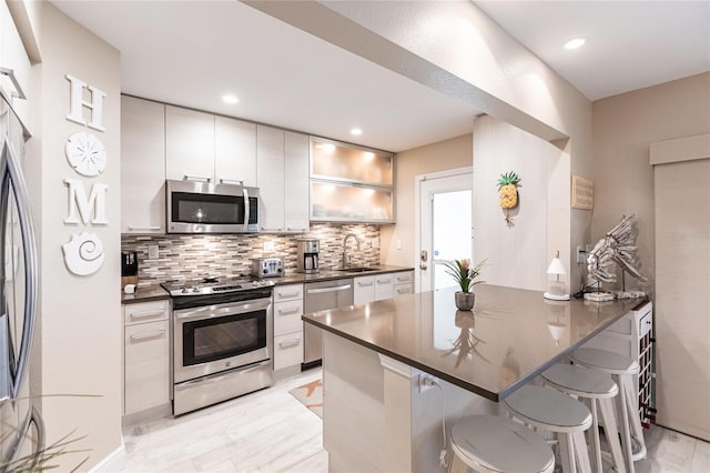 145 Avenida Messina Unit 3, Sarasota, FL 34242 - kitchen with a kitchen bar, appliances with stainless steel finishes, tasteful backsplash, white cabinets, and sink