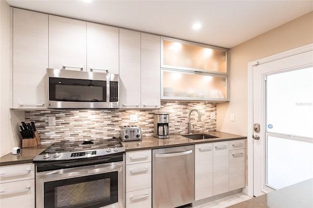 145 Avenida Messina Unit 3, Sarasota, FL 34242 - kitchen featuring white cabinetry, stainless steel appliances, dark stone countertops, tasteful backsplash, and sink