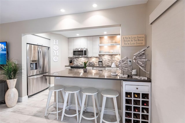 145 Avenida Messina Unit 3, Sarasota, FL 34242 - kitchen with a kitchen bar, white cabinetry, stainless steel appliances, and tasteful backsplash