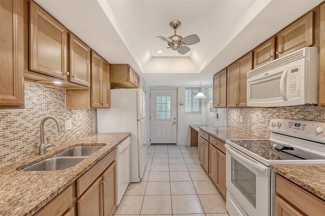 kitchen with white appliances, a raised ceiling, ceiling fan, sink, and light tile patterned flooring