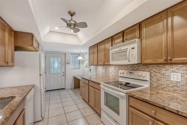 kitchen with white appliances, a raised ceiling, ceiling fan, light stone counters, and light tile patterned flooring