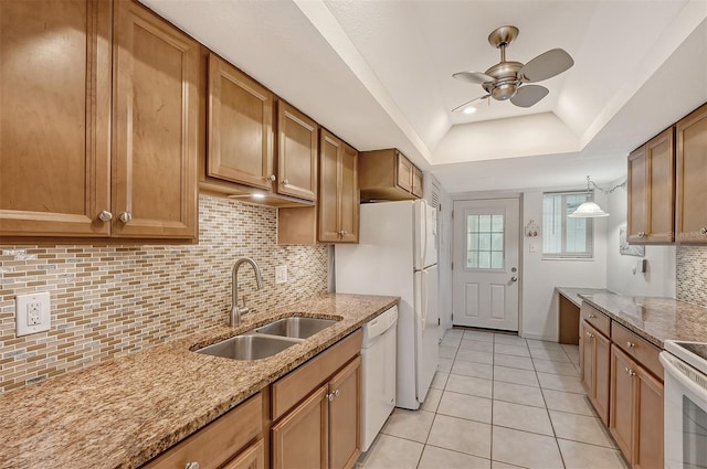 kitchen with white appliances, decorative light fixtures, light tile patterned floors, a tray ceiling, and sink