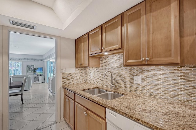 kitchen featuring light stone counters, dishwasher, backsplash, light tile patterned flooring, and sink