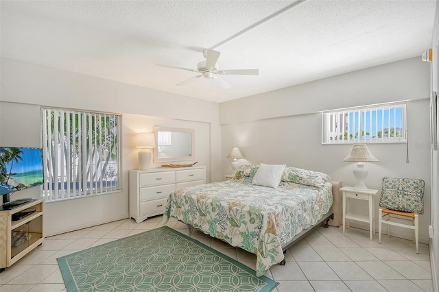 tiled bedroom with ceiling fan and a textured ceiling