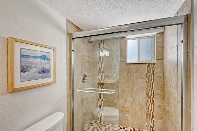 bathroom with toilet, an enclosed shower, and a textured ceiling