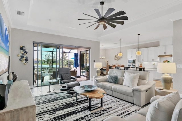 tiled living room featuring crown molding, ceiling fan, and a tray ceiling