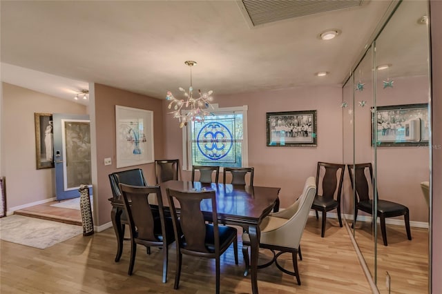 dining room featuring lofted ceiling, a chandelier, and light hardwood / wood-style floors