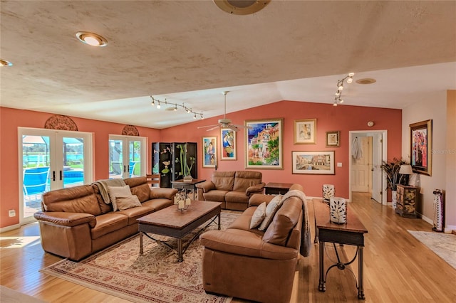 living room featuring ceiling fan, lofted ceiling, light hardwood / wood-style flooring, and french doors