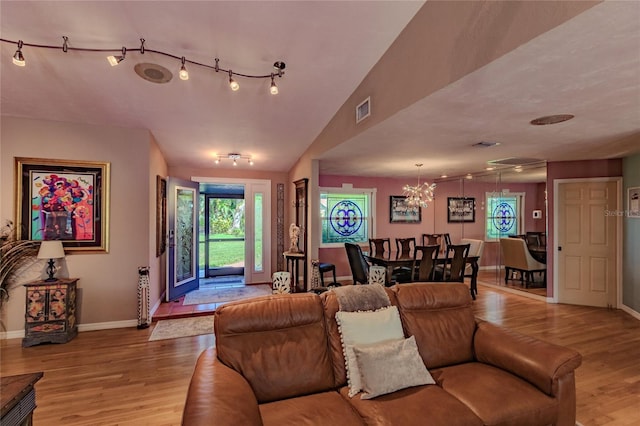 living room featuring a chandelier, lofted ceiling, and light hardwood / wood-style floors