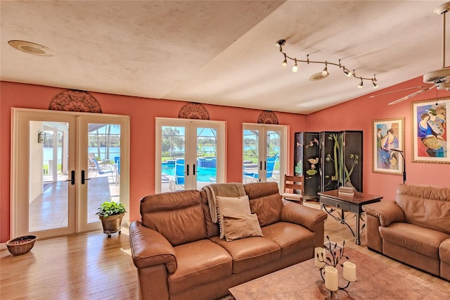 living room featuring ceiling fan, lofted ceiling, light hardwood / wood-style flooring, and french doors